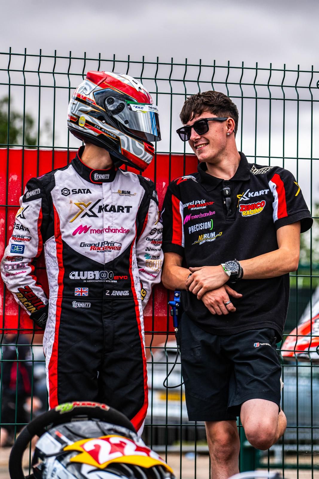 Zak in his helmet chatting with an X-Kart team member by the fence
